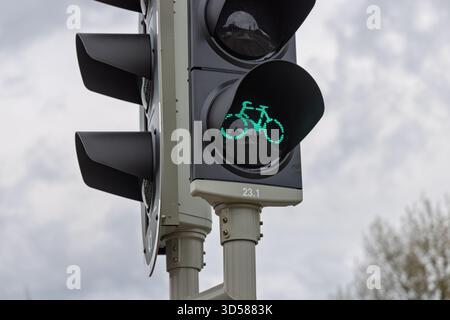 Vista ravvicinata di un moderno semaforo olandese che mostra un segnale verde con un'icona della bicicletta, che indica il permesso ai ciclisti di procedere. Foto Stock