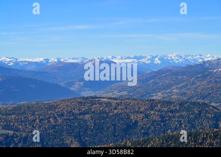 Vista panoramica delle valli boscose e delle montagne innevate di Salisburgo sotto un cielo azzurro. Foto Stock
