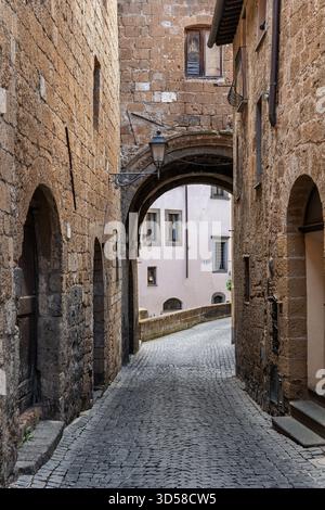 Italia - Orvieto - arco medievale su stradine acciottolate - tranquillo passaggio in pietra che si snoda attraverso gli storici Foto Stock