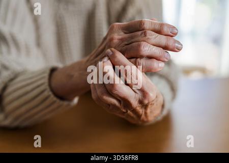 Donna anziana con artrite strofinando le mani Foto Stock