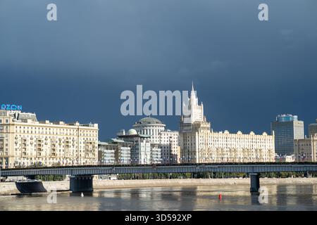 25 agosto 2025, Mosca, Russia. Lo skyline mostra una serie di stili architettonici, con una guglia visibile tra nuvole scure sul fiume Foto Stock
