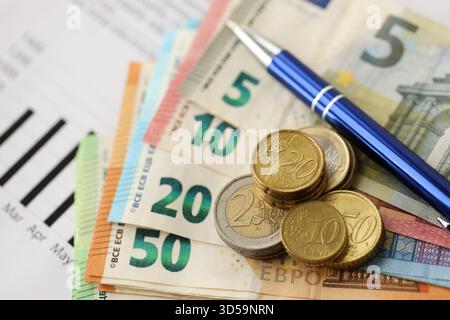 Banconote e monete in euro dell'unione europea con bolletta dell'elettricità sul tavolo da vicino Foto Stock