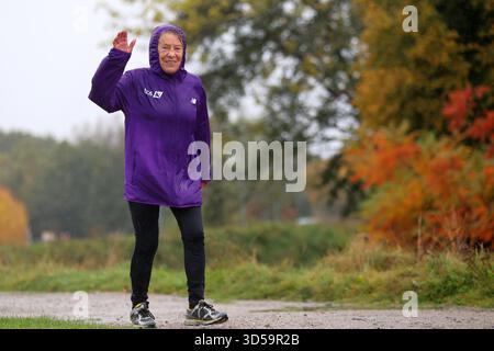 Donna anziana attiva che sventola in un giorno d'autunno piovoso Foto Stock