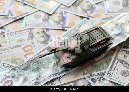 Carro armato su banconote da cento dollari schiacciate. Contesto del finanziamento di guerra e del prezzo di supporto militare per gli Stati Uniti d'America Foto Stock