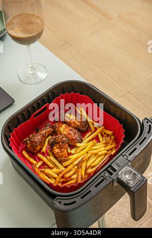 Un piatto combinato presenta ali di pollo glassate disposte in un semicerchio intorno a un mucchio di patatine fritte, con condimento ranch per l'immersione Foto Stock