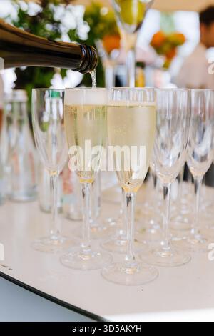 Vino frizzante versato in flute di champagne in un evento all'aperto, bolle lievitanti Foto Stock