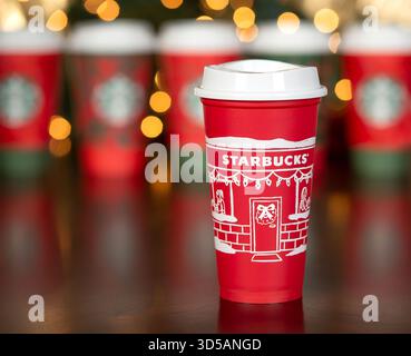 Dallas, Texas - 14 novembre 2025: Starbucks Coffee drink nella tazza rossa riutilizzabile progettata nel 2025. Bicchieri di carta monouso sullo sfondo. Vacanza boke Foto Stock
