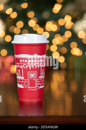 Dallas, Texas - 14 novembre 2025: Bevanda Starbucks nella tazza rossa progettata nel 2025, una tazza festosa e riutilizzabile per le vacanze. In mostra contro il bokeh ba natalizio Foto Stock