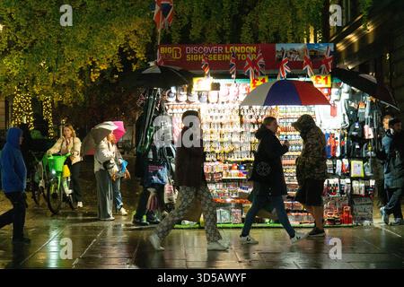 Meteo nel Regno Unito, 14 ottobre 2025: Mentre le luci di Natale e le vetrine illuminano le strade piovose di Oxford Street mentre turisti e gente del posto fanno acquisti il venerdì sera, approfittando di alcuni prezzi scontati disponibili in vista del Black Friday. Crediti: Anna Watson/Alamy Live News Foto Stock
