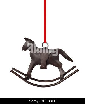 Ornamento natalizio a dondolo in ghisa scura appeso al nastro rosso ritaglio isolato su sfondo bianco, utilizzato per le decorazioni delle festività natalizie Foto Stock