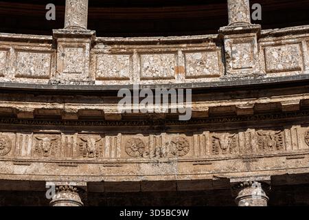 Vista ravvicinata di un fregio rinascimentale decorato che mostra intricati disegni e bucrania nel cortile circolare del Palazzo di Carlo V a Granad Foto Stock