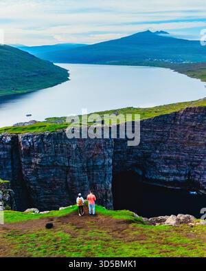 Una coppia visita la cascata Bosdalafossur, che cade direttamente nell'oceano. Lago Sorvagsvatn a Vagar, Isole Faroe, Danimarca, Europa. Foto Stock