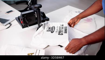 African-American Man Screen Prints maglietta personalizzata con logo alla Heat Press Factory. Foto Stock
