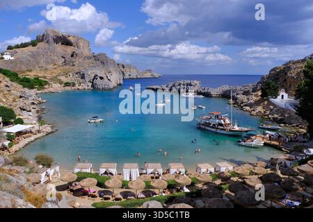 Lindos Rodi: Baia di San Paolo, cappella Agios Pavlos, castello dell'acropoli, spiaggia, nuotatori, ombrelloni, lettini e acque turchesi, Rodi, Grecia Foto Stock