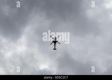Silhouette dell'elicottero Apache che vola contro il cielo nuvoloso Foto Stock