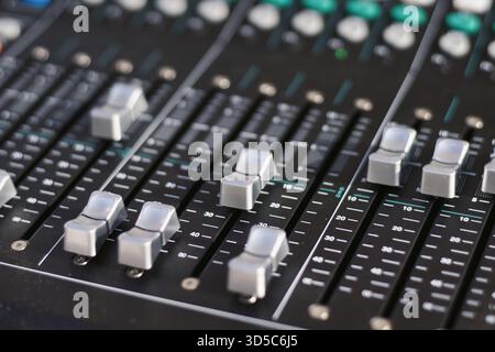 Uno scatto ravvicinato di pulsanti di bilanciamento del fader scanalati su una scrivania di missaggio in uno studio di registrazione professionale, messa a fuoco selettiva con sfondo sfocato Foto Stock