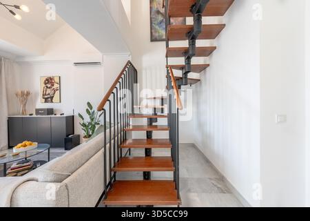 Soggiorno moderno con scala a chiocciola e pareti bianche in una lussuosa casa vacanze Foto Stock