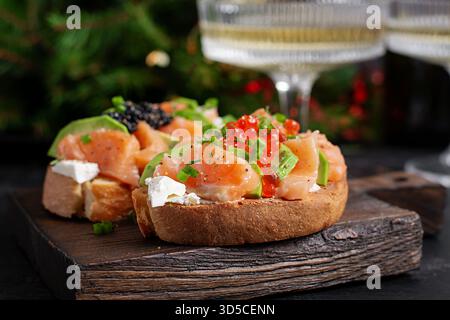 Antipasto di avocado e salmone sul tavolo di Natale. Tartine con pesce e caviale. Foto Stock