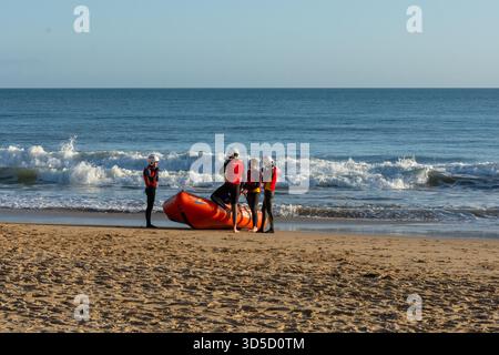 Bournemouth, Regno Unito - 8 novembre 2025: Bagnini del Bournemouth Lifeguard Corps con un Rescue Boat sulla sabbia di fronte al mare. Foto Stock
