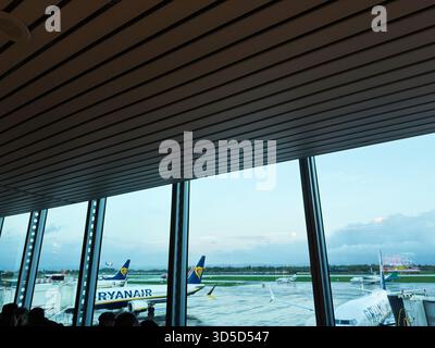 Manchester, Regno Unito - 4 ottobre 2025: Luminoso terminal aeroportuale con aerei Ryanair sull'asfalto all'esterno. Foto Stock