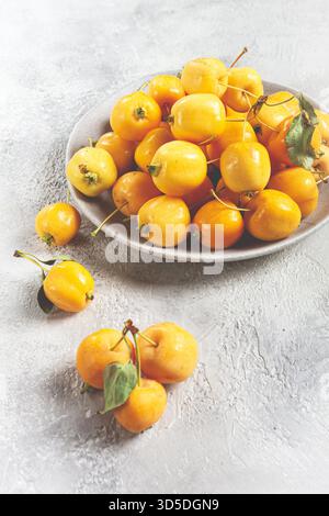 Mele piccole gialle, varietà cinese, su un piatto grigio, vista dall'alto, nessuna persona, Foto Stock