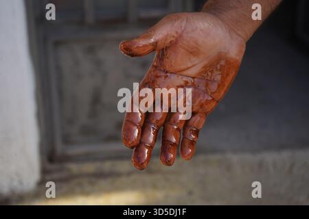 Primo piano estremo della mano allungata di un uomo, gocciolando con olio motore scuro e denso dopo un'attività di manutenzione automobilistica. Foto Stock