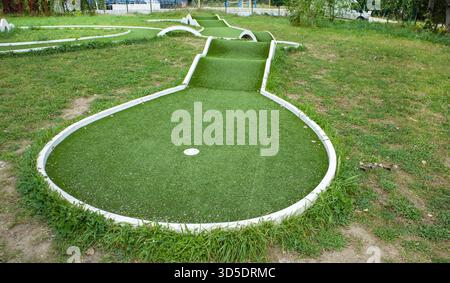 Campo da minigolf con erba artificiale e rampe vista della buca e degli ostacoli sfondo pulito per parchi divertimento per tutta la famiglia e annunci di intrattenimento con copia Foto Stock