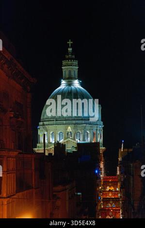 Un grande edificio con una cupola in cima e' illuminato di notte. L'edificio è circondato da altri edifici ed è una chiesa. L'illuminazione dà la costruzione Foto Stock
