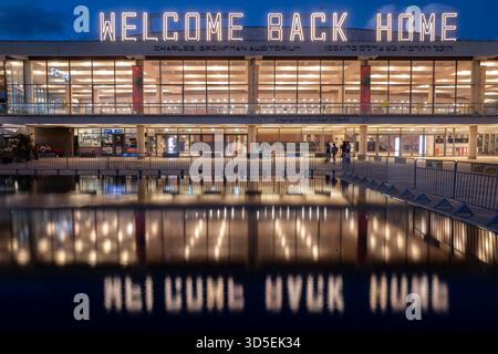 Tel Aviv, Israele. 15 novembre 2025. Civili israeliani visti davanti al Charles Bronfman Auditorium, che si trova accanto al Mann Auditorium, in Piazza Habima a Tel Aviv, Israele, mentre il grande cartello "Welcome Back Home" si illumina al tramonto di sabato 15 novembre 2025. Israele attende gli ultimi tre cadaveri che gli Hamas dovrebbero tornare per completare la prima fase del piano di pace sostenuto dagli Stati Uniti tra Israele e le forze di Hamas. La fase 2, quando avrà inizio, sarà cruciale, in quanto Hamas dovrebbe disarmarsi. Foto di Jim Hollander/UPI credito: UPI/Alamy Live News Foto Stock