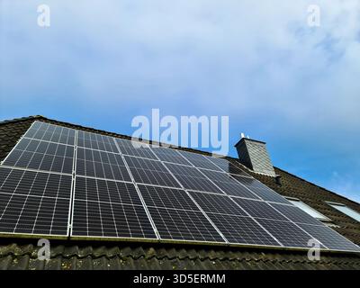 Pannelli solari fotovoltaici che coprono un tetto scuro, che sfruttano la luce solare per produrre energia elettrica pulita e rinnovabile per un'abitazione, promuovendo livi sostenibile Foto Stock