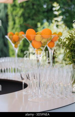 Alto centro martini con agrumi sopra file di flauti di champagne in un bar all'aperto Foto Stock