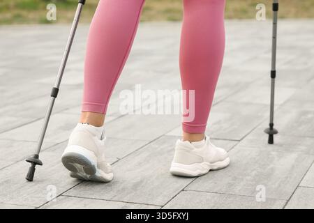 Donna sportiva che fa nordic walking per strada, vista sul retro Foto Stock