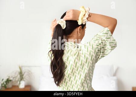 Bella donna con coda di cavallo e scrinchie in camera da letto, vista sul retro Foto Stock