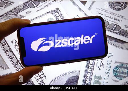 28 settembre 2025, Polonia: In questa foto, il logo della società Zscaler viene visualizzato su uno schermo di uno smartphone con le banconote in dollari statunitensi sullo sfondo. (Credit Image: © Piotr Swat/SOPA Images via ZUMA Press Wire) SOLO PER USO EDITORIALE! Non per USO commerciale! Foto Stock