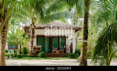 Un incantevole bungalow sull'isola di Koh Kood è annidato tra palme ondeggianti. Questo paradiso tropicale invita i viaggiatori a rilassarsi e godersi serene vedute della natura e della vita da spiaggia in Thailandia Foto Stock