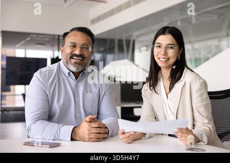 Buon uomo d'affari anziano e giovane consulente che posa al tavolo dell'ufficio Foto Stock