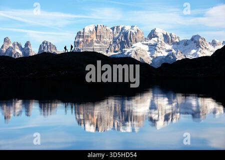 Spettacolare lago alpino Lago Nero vicino a Madonna di Campiglio in Italia, circondato da montagne coperte di neve fresca, escursionisti su un punto panoramico Foto Stock