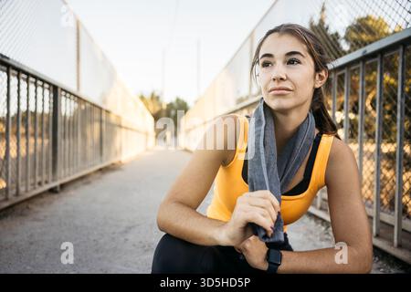 Giovane donna che si prende una pausa dopo aver corso, sembra determinata e concentrata Foto Stock