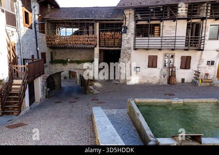 Belle e tradizionali case antiche del villaggio rango in provincia di Trento vicino al lago di Garda in Italia, vecchie case coloniche, attrazioni turistiche, grande fontana Foto Stock
