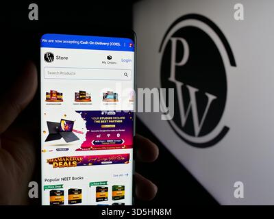 In questa illustrazione fotografica, una persona ha in mano un cellulare con la pagina web della società indiana Physics Wallah Limited (PW) sullo schermo davanti al logo. Foto Stock