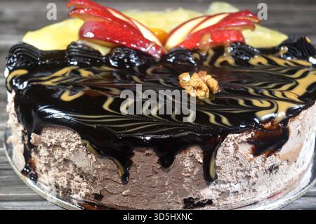 Torta di compleanno composta da due metà diversi pezzi, torta cremosa spugnosa per le celebrazioni, cioccolato fondente, caramello, panna alla vaniglia montata, fette di ananas Foto Stock