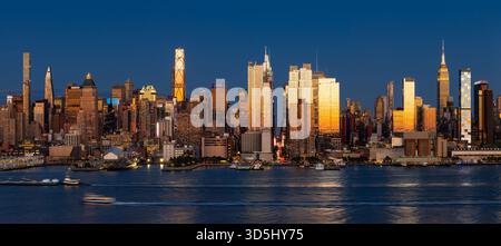 Vista panoramica serale dello skyline di Midtown Manhattan da New York attraverso il fiume Hudson, con grattacieli illuminati dall'ultima luce del tramonto Foto Stock