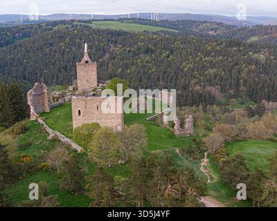 Le maestose rovine del castello di Luc e della cappella che sorgono su una collina, circondate da un paesaggio verde con turbine eoliche visibili sullo sfondo Foto Stock