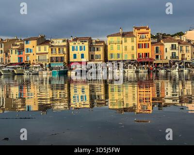 Città portuale di Cassis, nel sud della francia, che riflette edifici colorati e barche da pesca Foto Stock