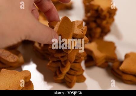 Una persona impila biscotti di pan di zenzero a forma di stella l'uno sull'altro. E' una festa di Natale. Preparatevi per la cottura delle vacanze. Foto Stock