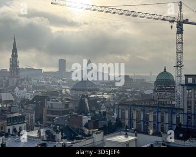 Belgio, Bruxelles, 31 dicembre 2024; paesaggio urbano di Bruxelles con gru edile, edifici storici e nebbia, che mostra lo sviluppo urbano e storico Foto Stock