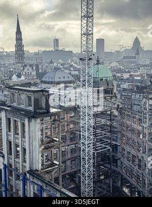 Belgio, Bruxelles, 31 dicembre 2024; cantiere con gru e ponteggi metallici nel paesaggio urbano di bruxelles con edifici storici e. Foto Stock