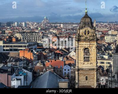 Belgio, Bruxelles, 31 dicembre 2024; paesaggio urbano di bruxelles con una storica torre dell'orologio e la basilica del cuore sacro Foto Stock