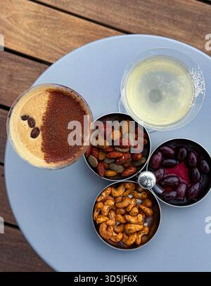Cocktail, noci e olive serviti come antipasti per l'happy hour su un tavolo grigio Foto Stock