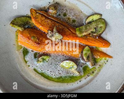 Piatto di verdure gourmet con carote arrosto, funghi a fette, salsa verde e schiuma su un piatto Foto Stock